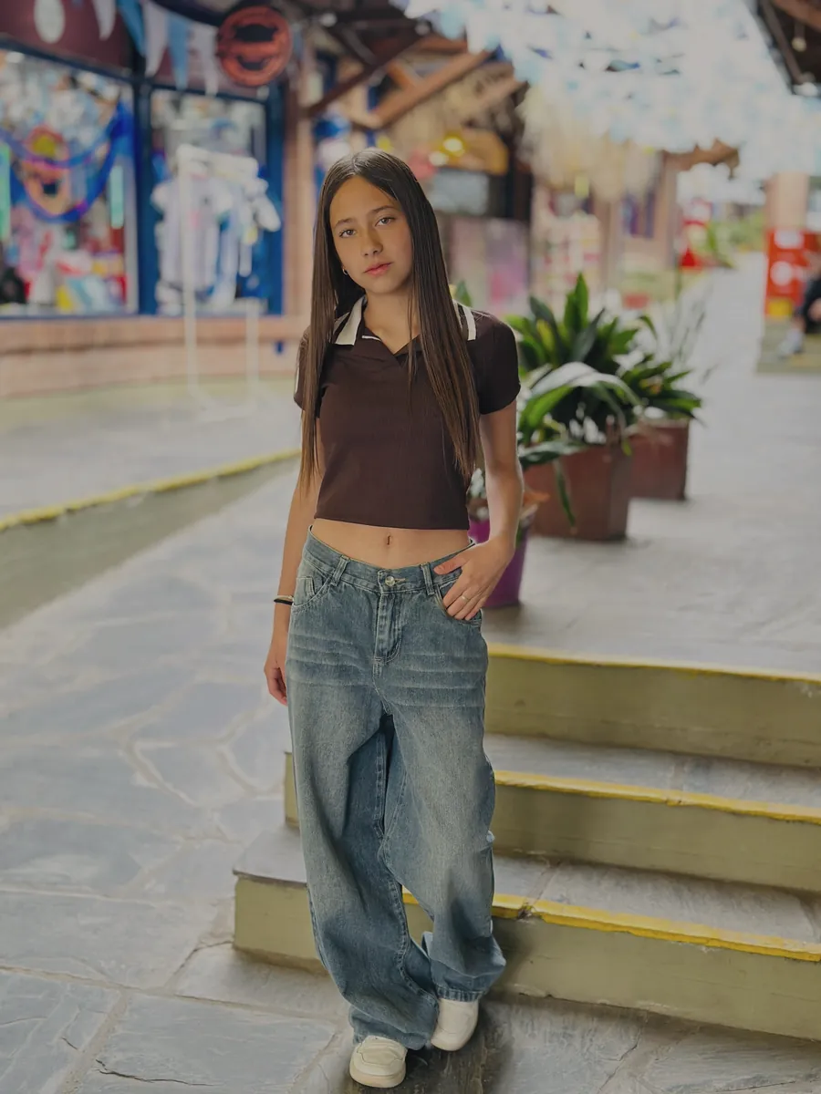 Chica de pelo largo con remera blanca de mangas marrones, sentada en una escalera de la peatonal